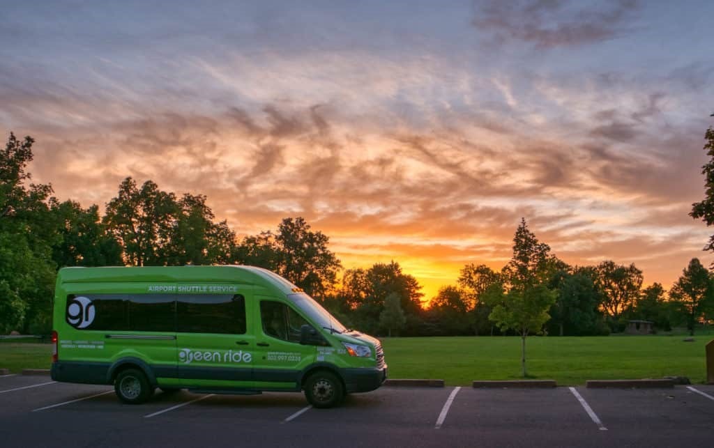blog-2 A GreenRide bus parked in front of a field with a sunset overhead.